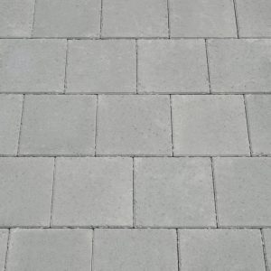 Grey concrete paving blocks arranged in a grid on a sidewalk or pavement surface.