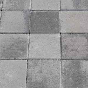 Gray concrete paving tiles arranged in a grid with visible joints and weathered surfaces.