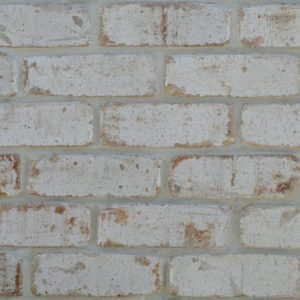 Close-up of a whitewashed brick wall with light gray mortar and weathered bricks in pale tones.