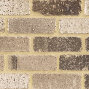 Close-up of a weathered brick wall with tan and brown bricks and light tan mortar