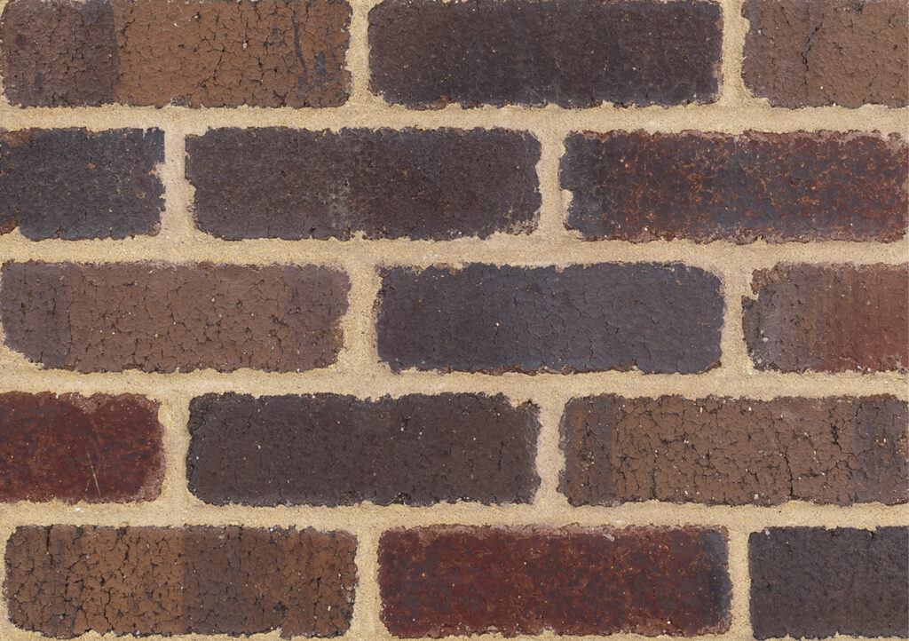 Close-up of a brown brick wall with light tan mortar.