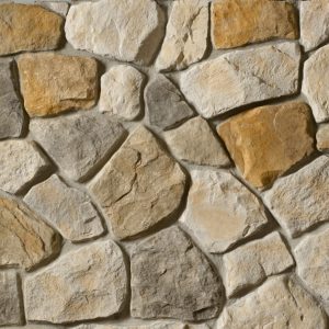 Stone wall made of irregular beige, tan, and brown rocks with light mortar lines that separate the stones.