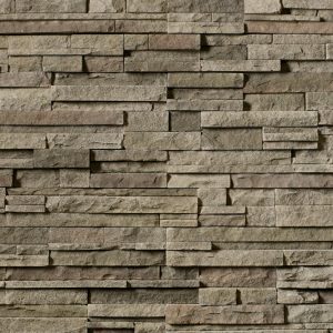 A textured stone wall made of rectangular, stacked stones in gray-brown tones.