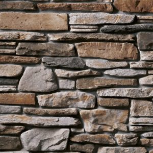 Stone masonry wall with irregular flat stones in beige, gray, and brown tones.
