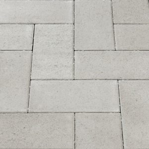 Gray concrete pavers arranged in an interlocking rectangular pattern forming a paved surface, like a sidewalk or patio hold.