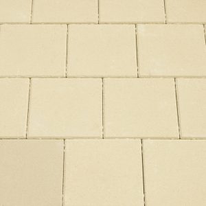 Beige rectangular paving bricks arranged in a grid with thin mortar joints, forming a sidewalk pattern.