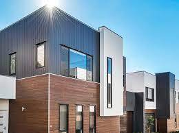 Row of modern two-story townhouses with brick and white siding under a clear blue sky.